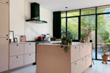 a light-filled pink kitchen with MDF cabinets, neutral countertops, a white marble backsplash and black appliances