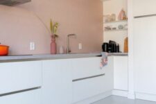 a minimalist kitchen in dusty pink, with sleek white cabinets, grey stone countertops is a chic and lovely space