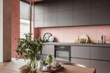 a minimalist kitchen in pink, with sleek graphite grey cabinetry, a concrete ceiling and a small dining space
