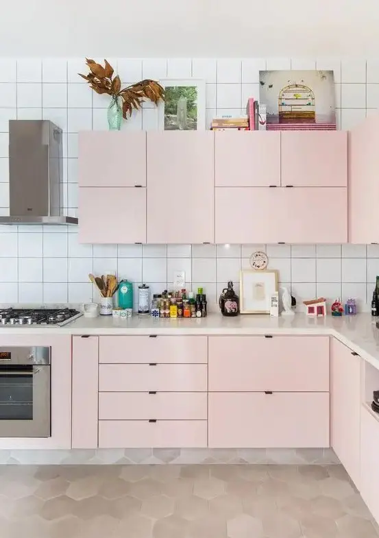 A modern kitchen in light pink, with a white tile backsplash and built in appliances is all the chic