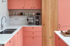 a pink kitchen with a white subway tile backsplash, a stained cabinet and no handles plus a shelf for storing decor