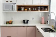 a two-tone kitchen with upper white and lower pink cabinets, a white tile backsplash and white stone countertops is clean and chic