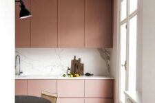 an ultra-minimal dusty rose kitchen with sleek cabinets, a white marble backsplash and countertops plus touches of black
