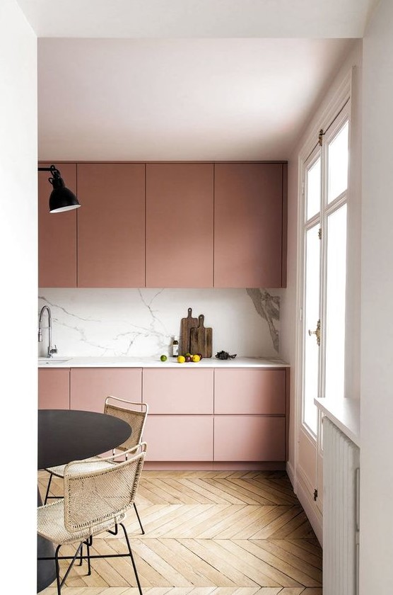 An ultra minimal dusty rose kitchen with sleek cabinets, a white marble backsplash and countertops plus touches of black