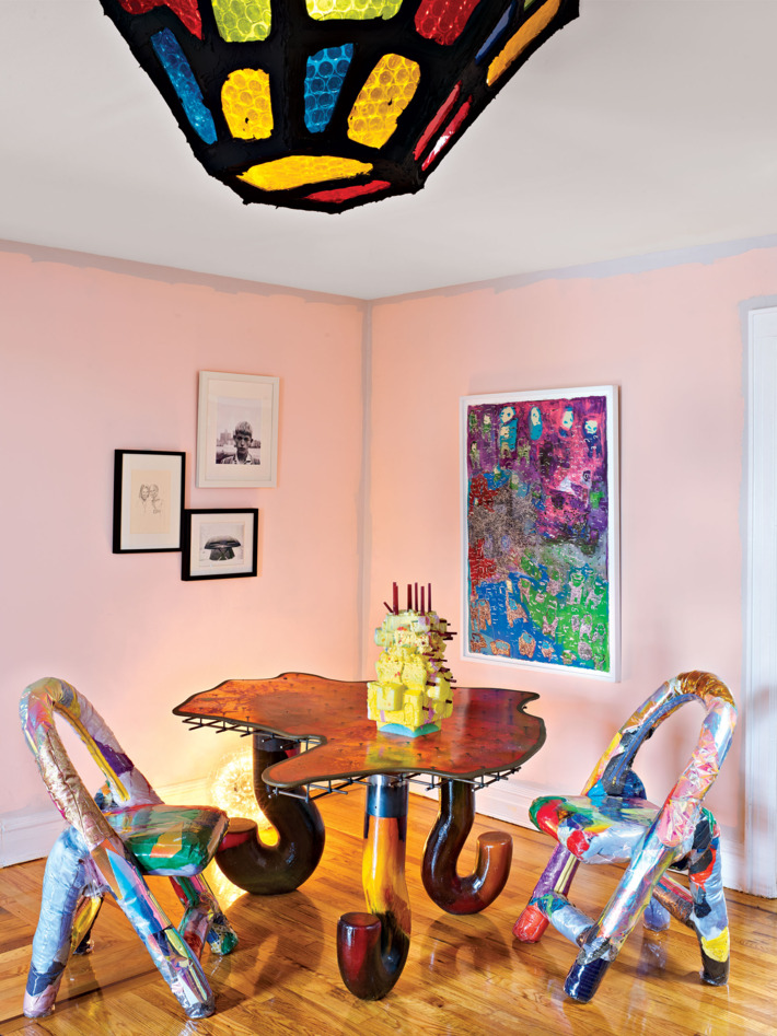 The dining room is super colorful, with bold chairs, an artwork, a pendant lamp and look at these table legs