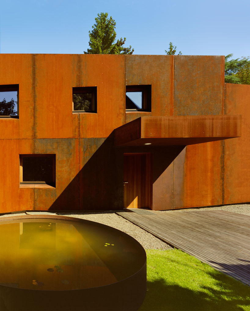 The house is clad with rust colored metal, which is highlighted with naturally neutral surroundings