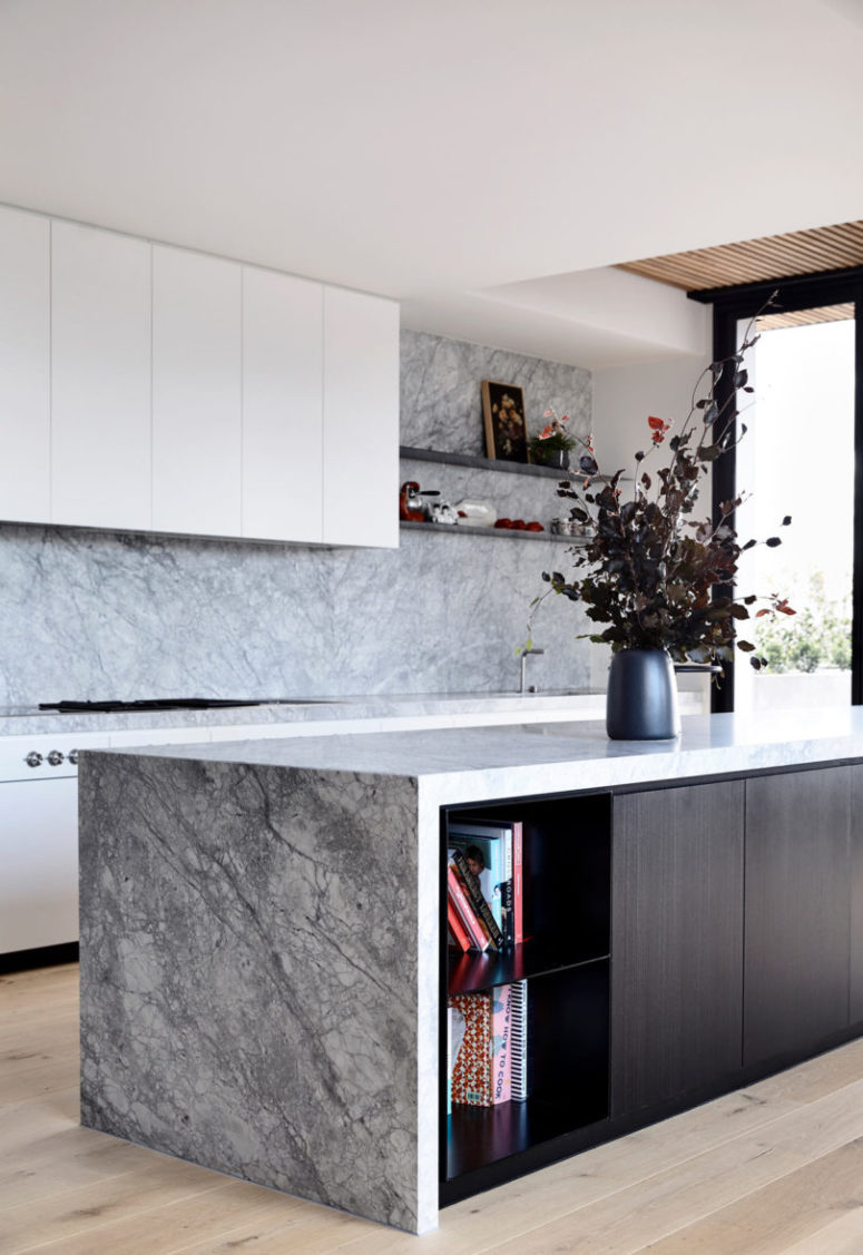 The kitchen features white cabinets, stone surfaces and a dark kitchen island