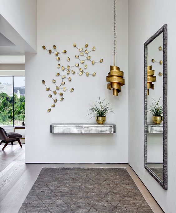 a silver floating console table, a sculptural brass lamp and a botanical artwork for a wow effect