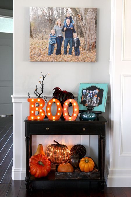 a small console table with colorful faux pumpkins, a lit up pumpkin and marquee letters for a bold look
