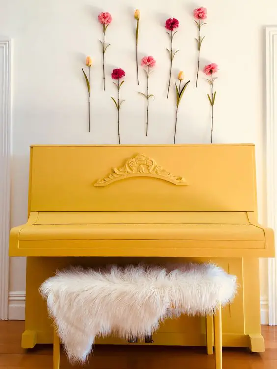 a yellow piano with a faux fur stool and faux blooms attached to the wall for a feminine feeling
