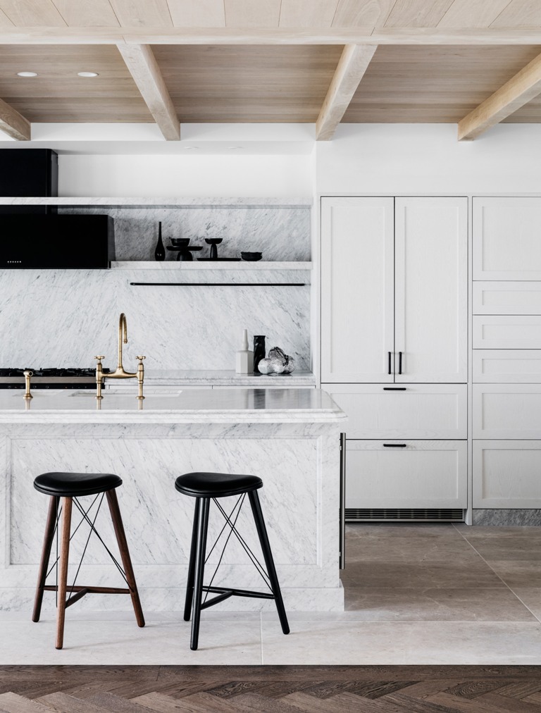 The kitchen is done with white cabinets, white marble and black touches for a dramatic feel