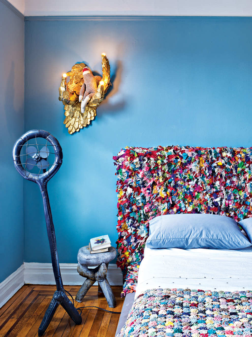 The master bedroom features a super colorful headboard and a matching bedspread, crazy furniture and lamps designed by the couple