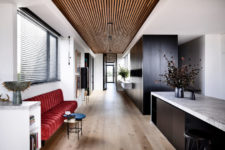03 There’s a large dark storage unit in the kitchen and a red upholstered bench as a bold touch