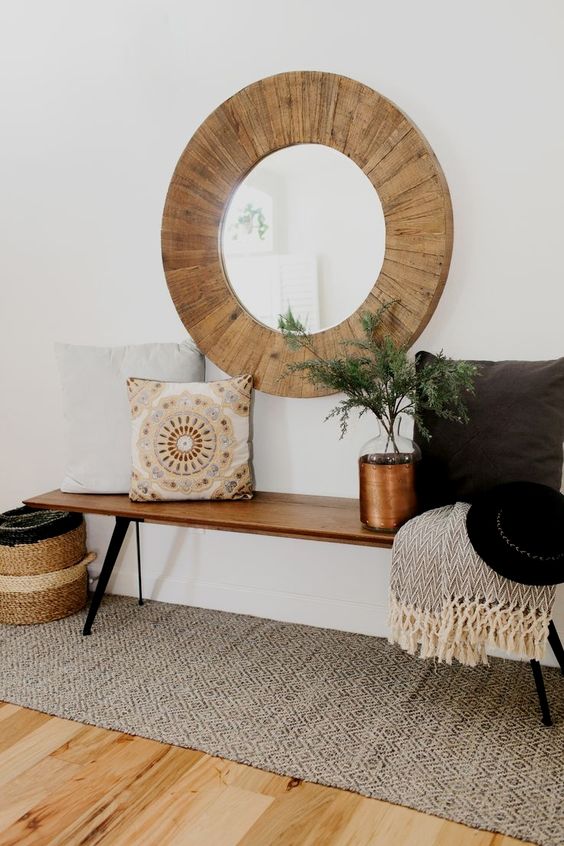 a large round mirror clad with wood is ideal for a rustic or boho chic space, it will add coziness