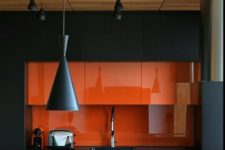 03 a minimalist kitchen in black and orange, with a glass backsplash and cool pendant lamps in black