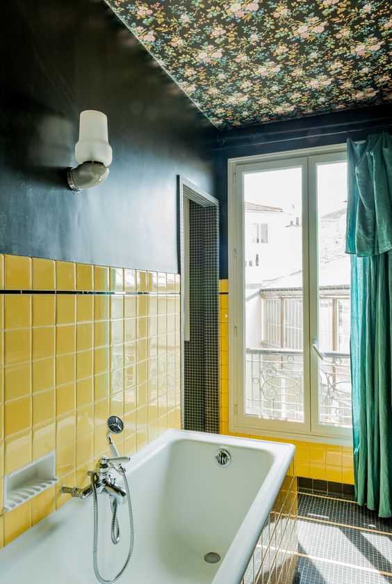 Navy wallpaper paired with sunny yellow tiles plus a green curtain make the bathroom super bright and eye catchy