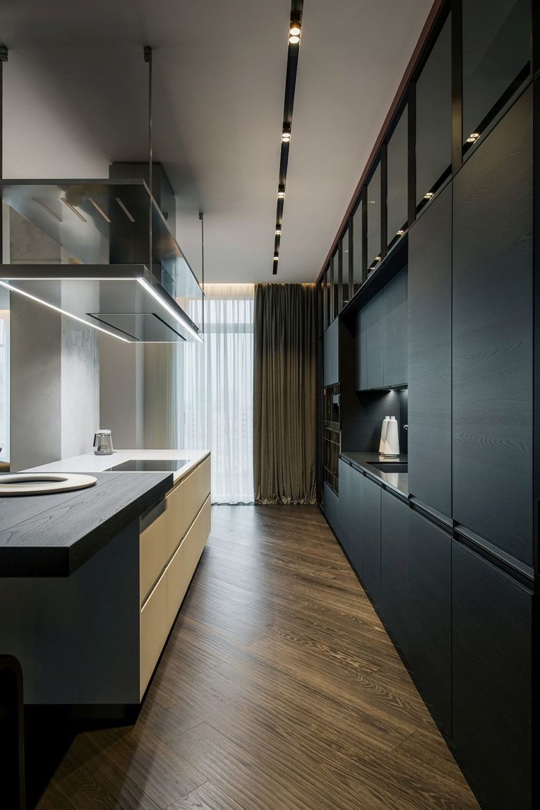 The kitchen is done with sleek black plywood cabinets and a white kitchen island with a plywood countertop