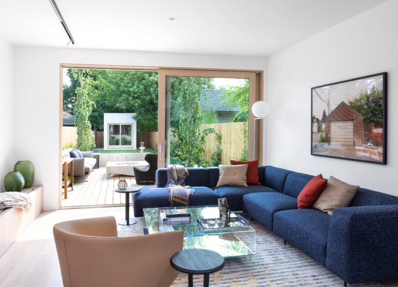 The living room is a united indoor-outdoor space with a bold blue corner sofa, catchy furniture and storage items