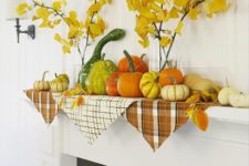 04 a fall mantel with a lot of pumpkins and gourds and yellow leaves in clear vases
