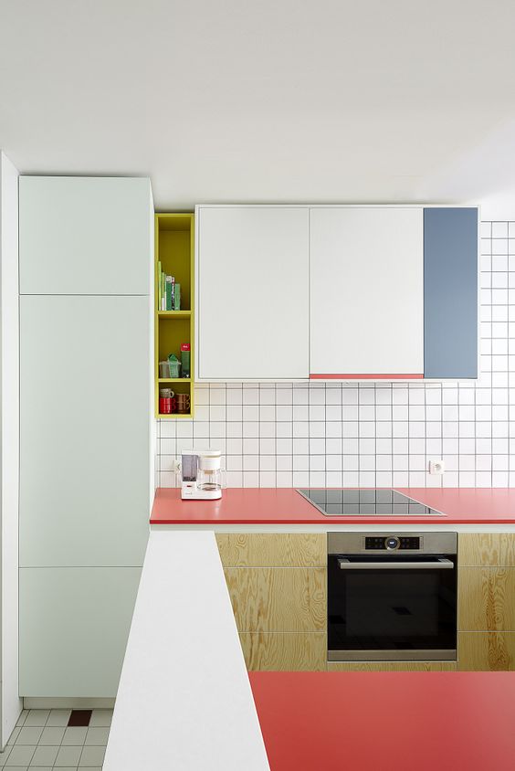 a minimalist color block kitchen with coral, aqua and blue accents and white tiles with black grout