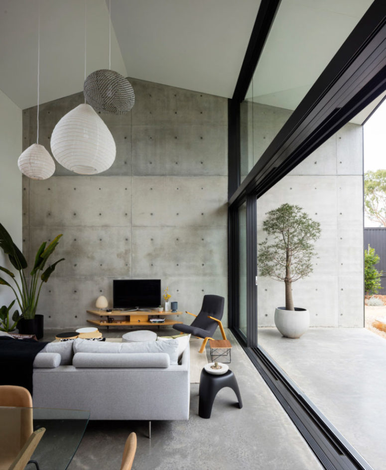 The living space is done in grey shades with black, with light-colored plywood