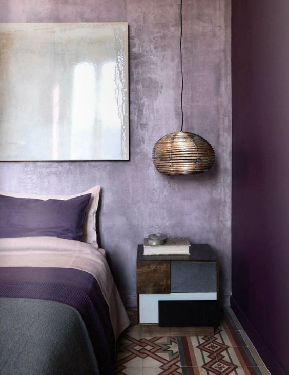 a bold color blocked bedroom with a bright purple wall and lavender plaster ones for an enchanting look