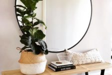 05 a large round mirror in a black frame and a wooden bench for a simple boho chic space
