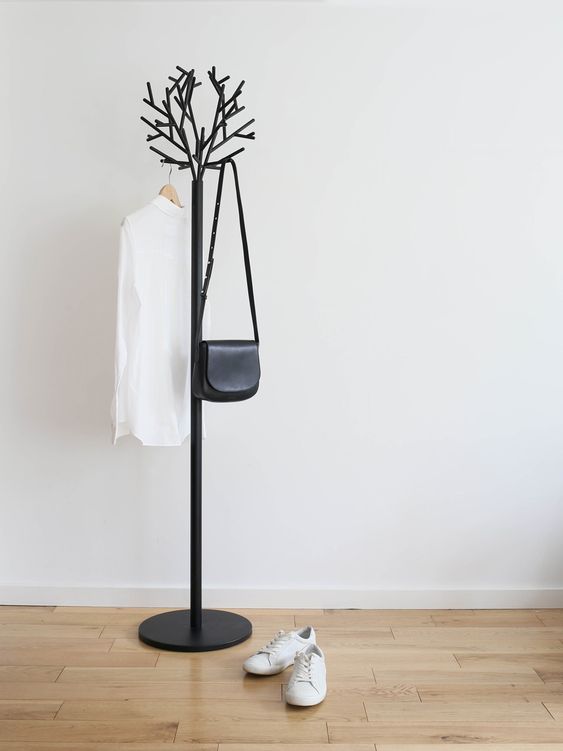a minimalist coat tree imitating a real tree, made of metal with a black finish for easy blending