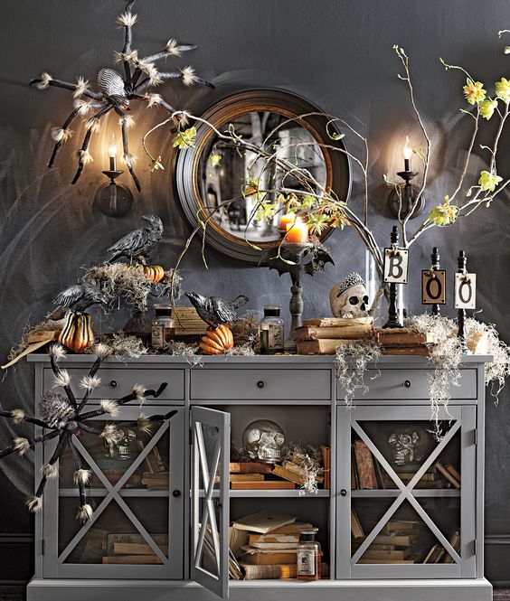 a moody Halloween console with giant spiders, fake pumpkins, skulls and candles