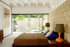 06 The master bedroom is opened up to outdoors with glass doors, there’s colorful furniture and an artwork