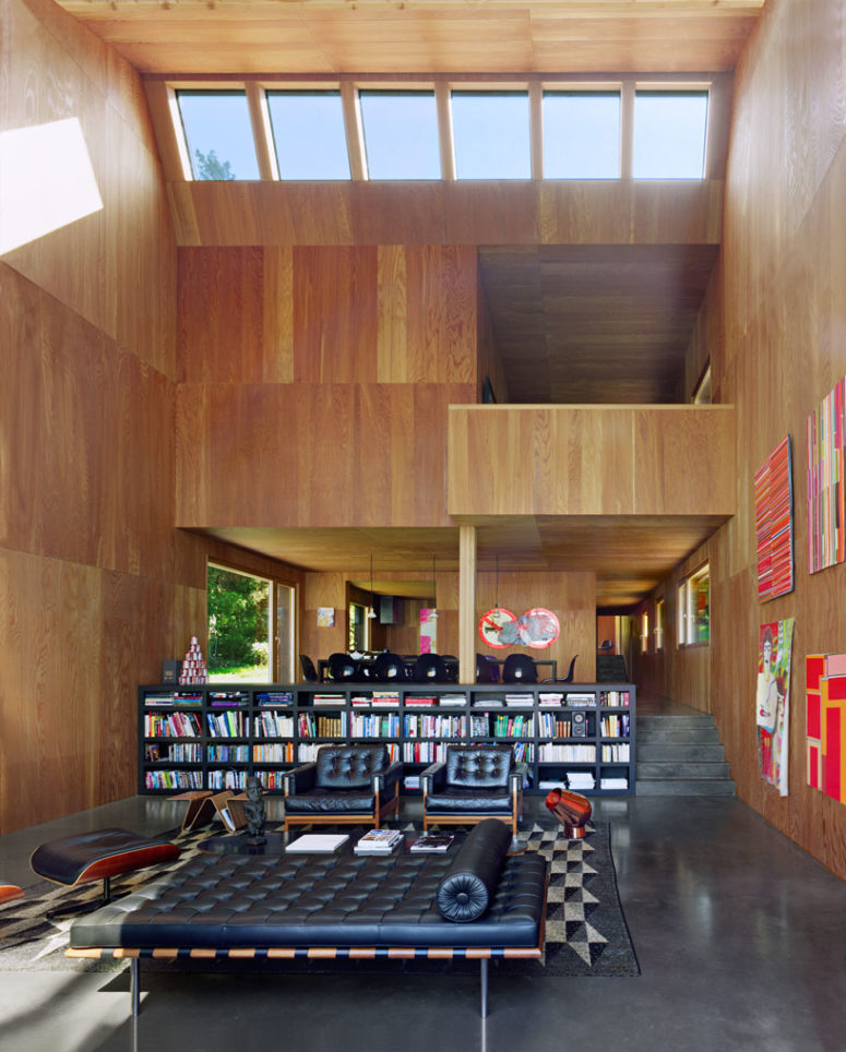 The space divider is a giant bookshelf and the upper floor features more private spaces
