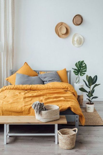 a boho bedroom with grey and yellow bedding that creates a contrasts and brings sunlight to the space