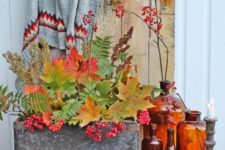 06 a stylish fall display with colorful bottles, candle holders, a concrete box with fall leaves and berries