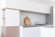 07 The kitchen is minimalist, in white and beige, with sleek cabinets and a concrete backsplash and countertops
