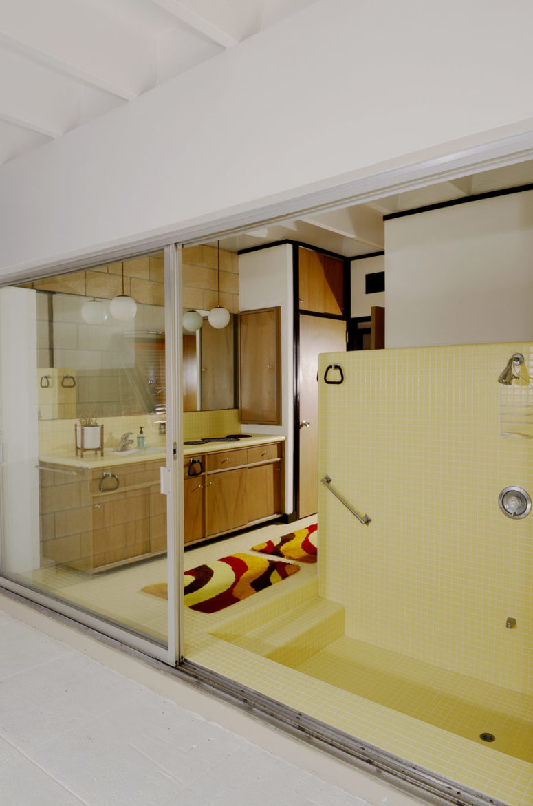 The master bathroom is very eye-catchy, with yellow tuiles and brown wooden furniture plus storage items