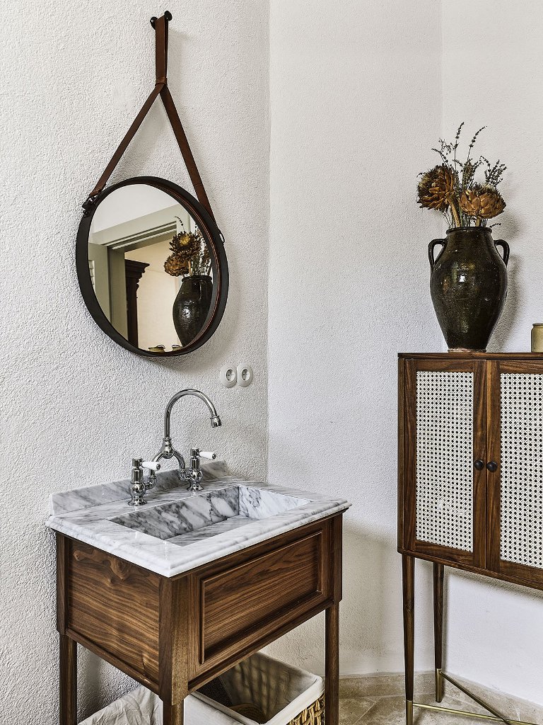 The master bathroom shows off a marble sink, wood and a cool colonial-style cabinet