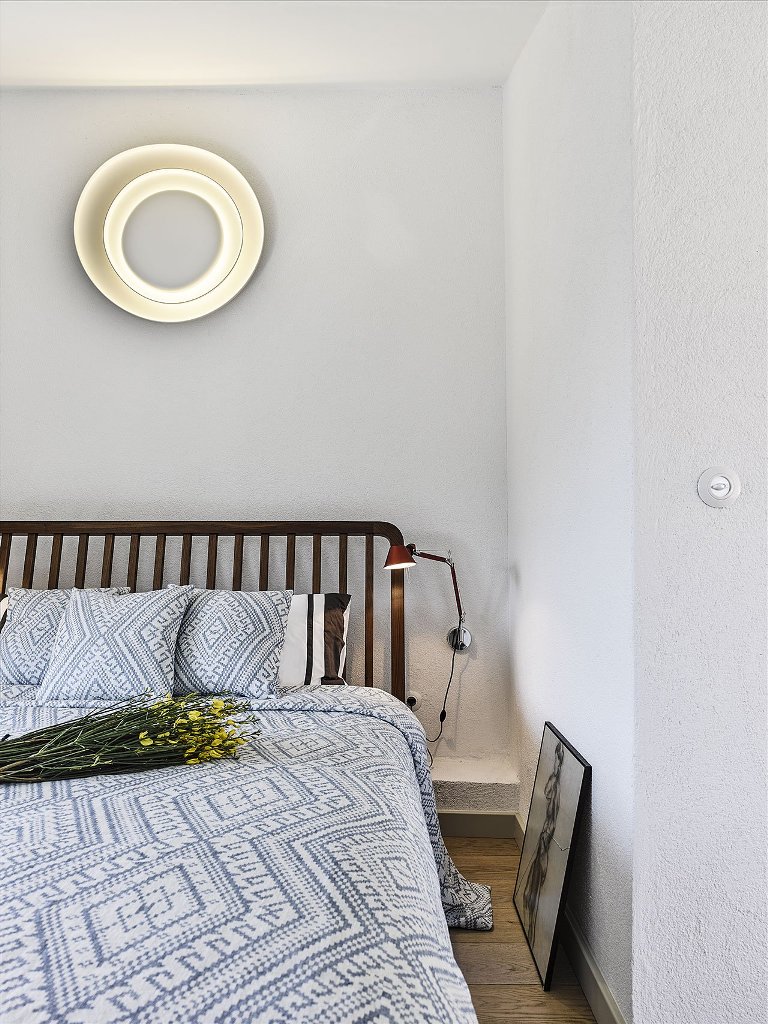 A guest bedroom is done with a large bed and a catchy wall lamp