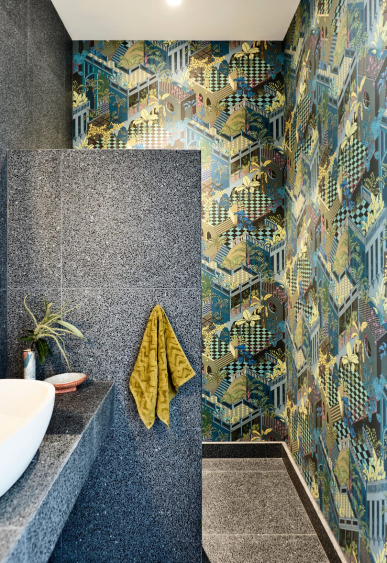 A powder room is done with extra bold printed wallpaper and stone-inspired tiles