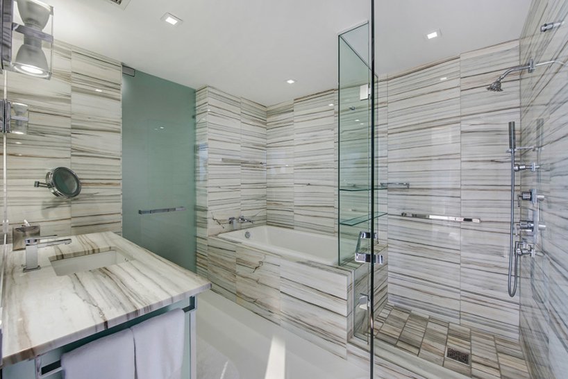 One of the bathrooms clad with marble completely and with a use of glass and metal