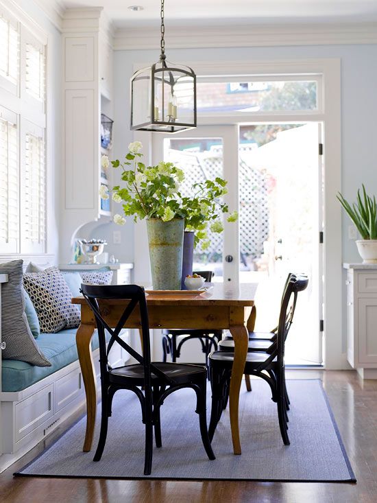 a comfy eating nook with a built-in banquette seating and a wooden table plus black chairs