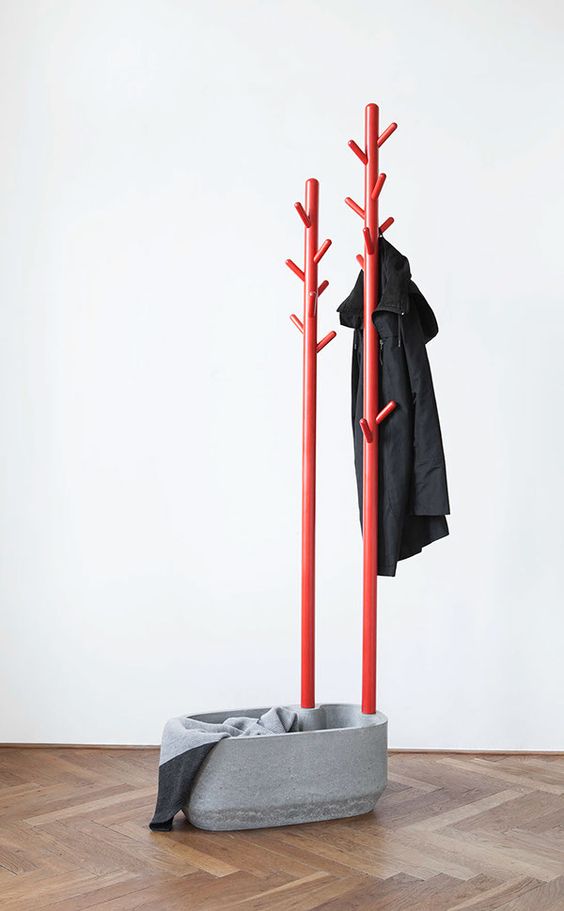 An ultra modern coat rack of a concrete bowl and red metal trees   hang your clothes and accessories on them and put something into the bowl, too
