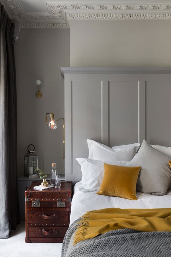 make your grey bedroom more interesting with mustard pillows and blankets and a mahogany nightstand