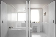 09 The bathroom is clad with white marble and is highlighted with black fixtures