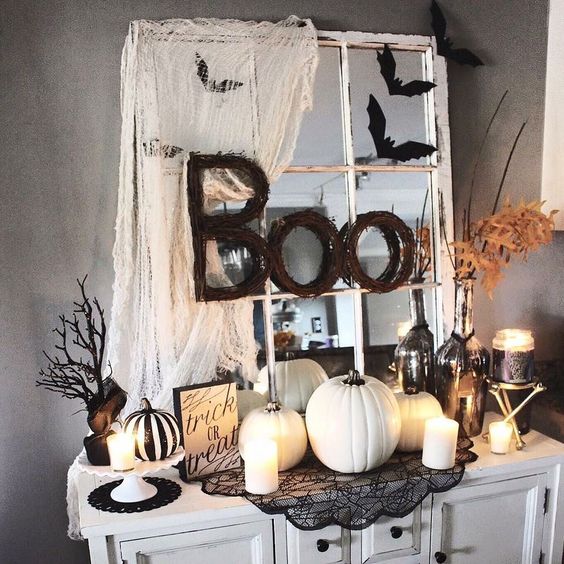 a Halloween console in black and white, with fake pumpkins, candles, lace and twig letters plus a window frame
