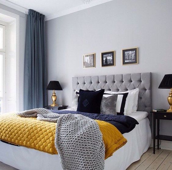 a grey and blue bedroom spruced up with a yellow blanket for a bright and cheerful look