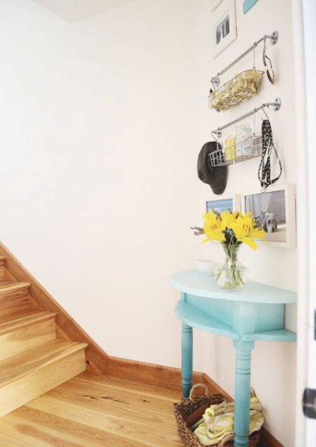 a stairwell landing is an awkward nook, it's decorated with a half table in blue and some hanging shelves