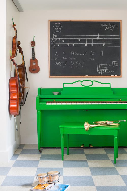 An emerald piano and stool, a chalkboard for making notes and other musical instruments for a music loving person