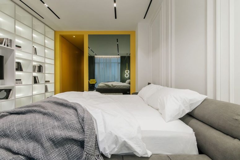 The second bedroom is all-white, with grey and yellow touches and there's an oversized storage wall unit