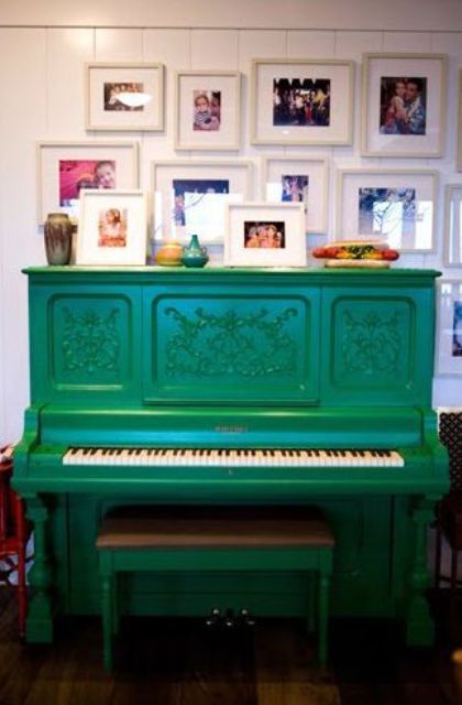 a bright emerald piano and stool and a display of family pics over the piano