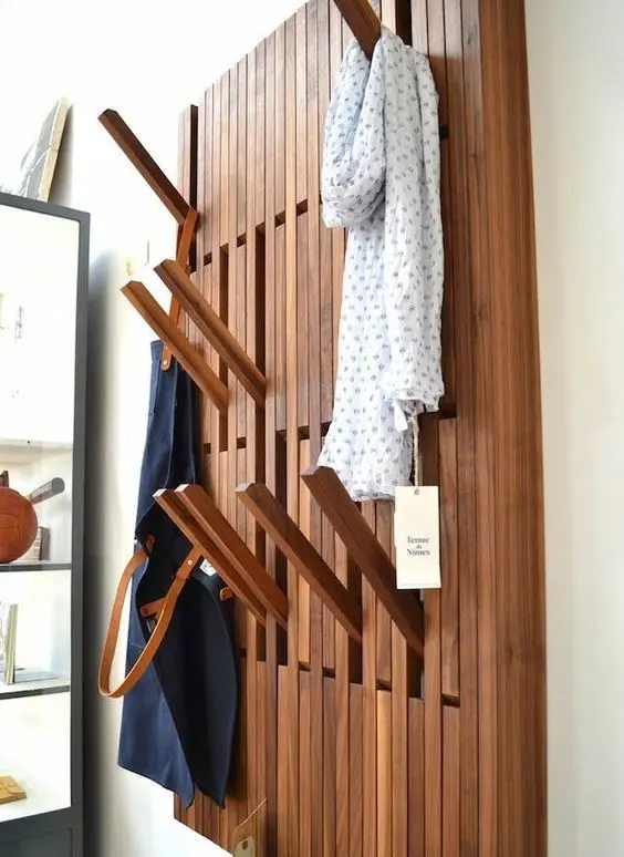 a creative wall-mounted clothes rack with wooden sticks that can be pulled out when needed and then hidden again